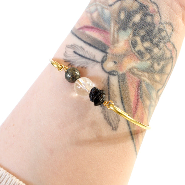 gold brass bangle with pyrite, quartz and black tourmaline beads worn on tattooed arm with white background