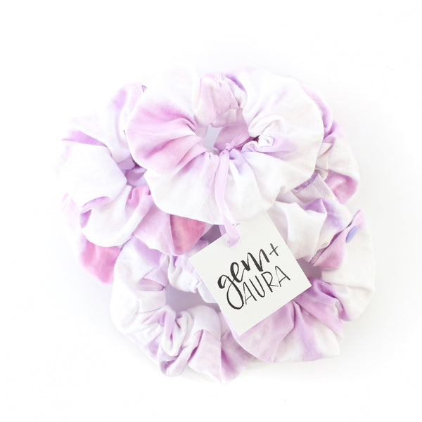 pile of purple and white scrunchies with a white background and a gem and aura tag on the top