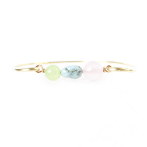 gold brass bangle with jade, larimar and rose quartz beads in the center. white background