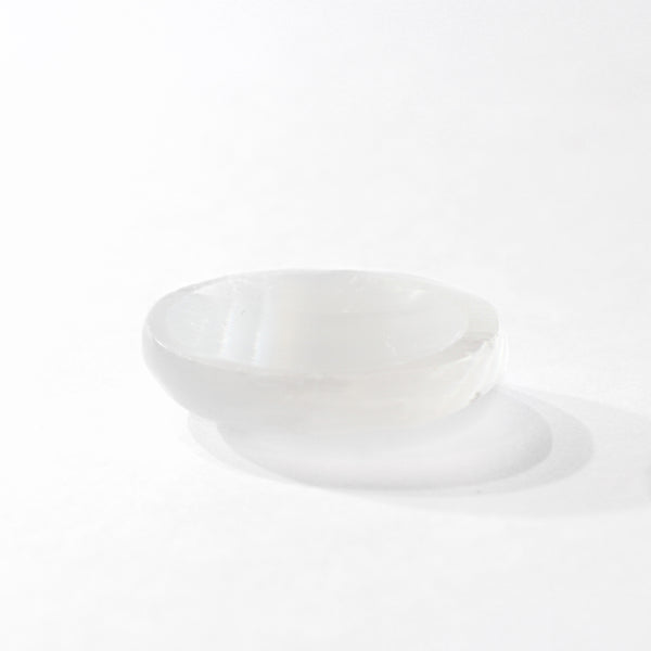 front view of selenite disc sitting on a white background. 