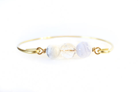 gold bangle with blue lace agate, howlite and quartz beads with white background