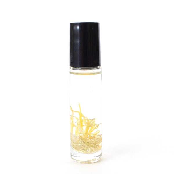 clear glass roller bottle with a black lid.  in the bottle there is an essential oil blend, and dried calendula, gold glitter and citrine chips. there is a white background.