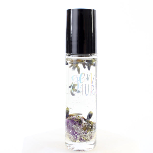 clear glass roller bottle with a black lid and a holographic gem + aura logo on it. bottle is filled with an essential oil blend and also contains silver glitter, dried lavender flowers, and amethyst chips. there is a white background.