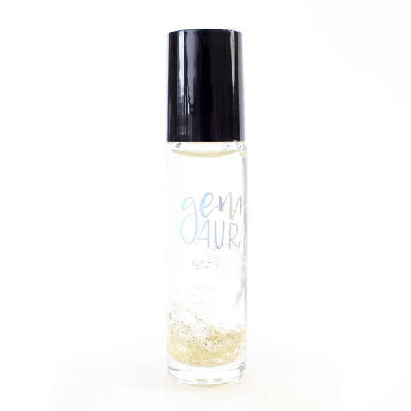 white background with a clear glass roller bottle with a black lid. the bottle has a holographic Gem+Aura logo. in the roller is clear quartz and gold glitter.