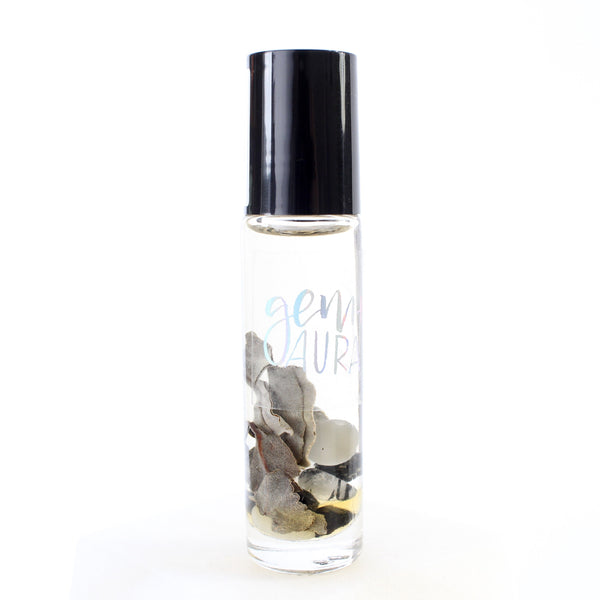 white background, clear glass oil roller bottle with a black lid. inside is dried sage, cats eye, black tourmaline and tourmalinated quartz in an oil blend. There is a holographic gem and aura logo on the bottle.