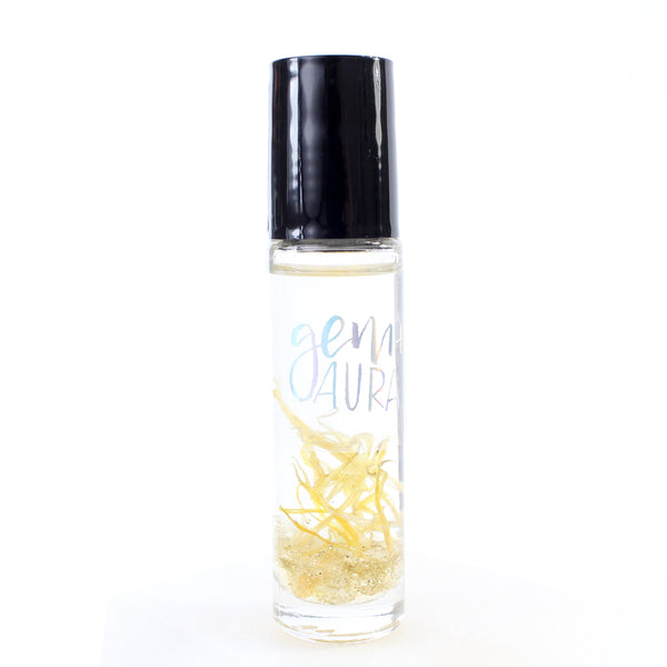 clear glass roller bottle with a black lid and a holographic gem + aura label on it. in the bottle there is an essential oil blend, and dried calendula, gold glitter and citrine chips. there is a white background.