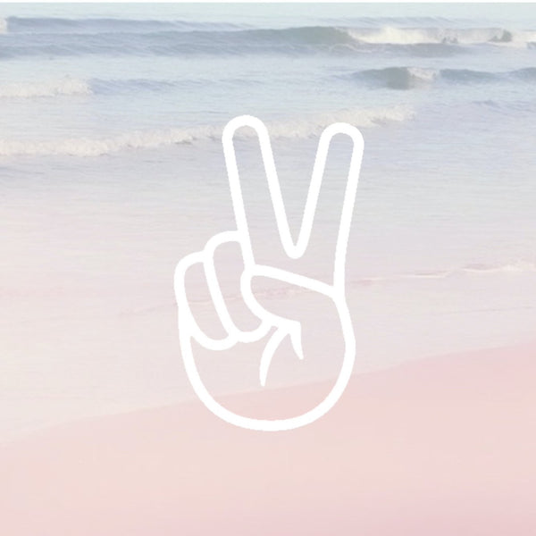 faded photo of the ocean shore with gentle waves, with a white overlay of a hand being held in a peace sign position