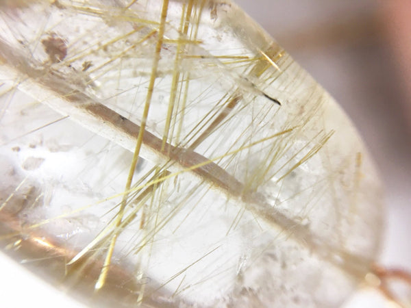 close up of gold rutile in a piece of clear quartz, gold rutilated quartz