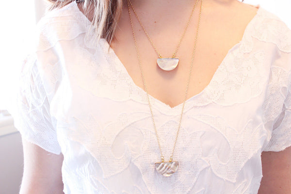 22" and 30" silvery rainbow half moon seashell necklaces on dainty gold chain modelled by white woman wearing white shirt, shoulder length brown hair with a white background