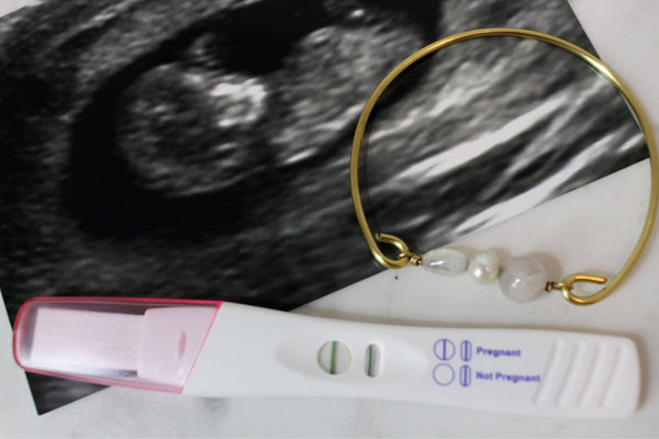 fertility bangle with gold brass wire, rose quartz, pearl and moonstone pictured with sonogram photo and positive pregnancy test