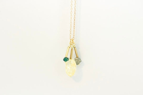 malachite, citrine and pyrite pendants strung on a dainty gold chain with a white background