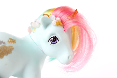 mint blue my little pony figurine with a rainbow coloured mane, an orange crystal horn and crystals trailing down her mane. white background, side profile