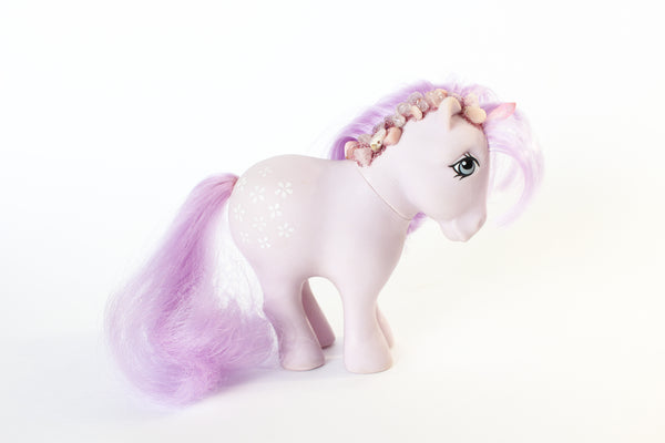 light purple my little pony figure with a pink quartz point for a unicorn horn, and pink and purple gemstones running down her mane. the gemstones have pink glitter between them. side view. white background