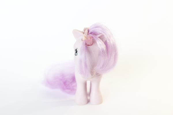 light purple my little pony figure with a pink quartz point for a unicorn horn, and pink and purple gemstones running down her mane. the gemstones have pink glitter between them. front view.  white background