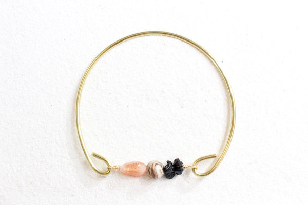 sunstone, petrified wood, and black tourmaline on a gold brass bangle